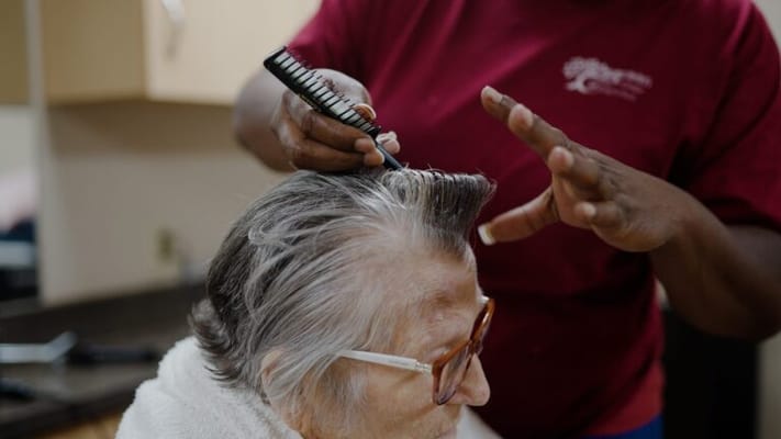 Staff member styling resident's hair in a salon area