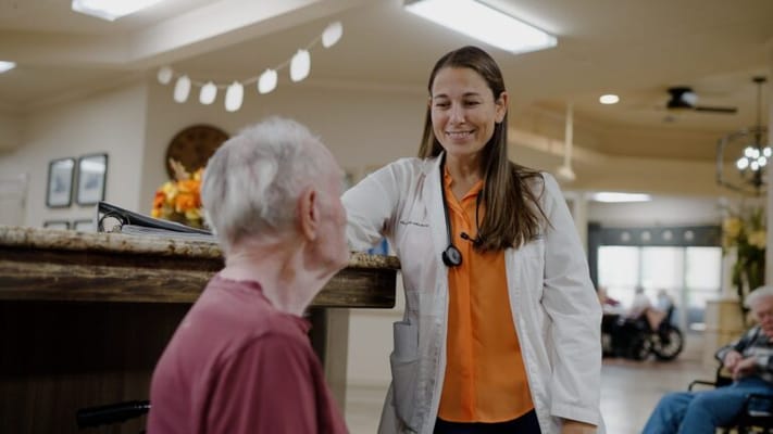 A staff member smiling while interacting with a resident in a common area