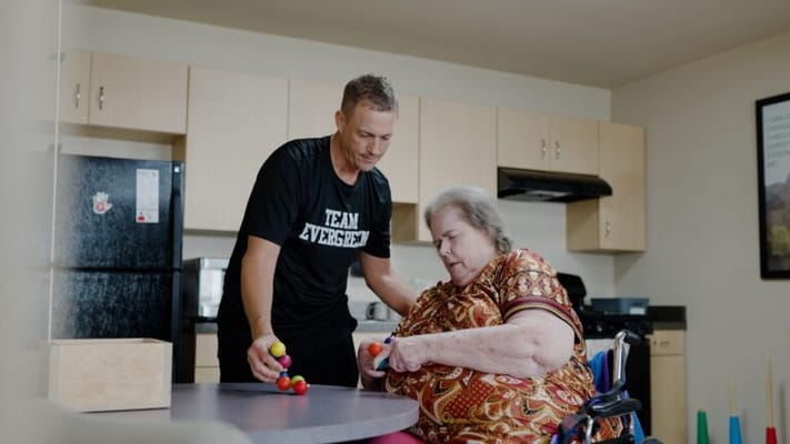 Staff assisting a resident with a colorful activity in a common area