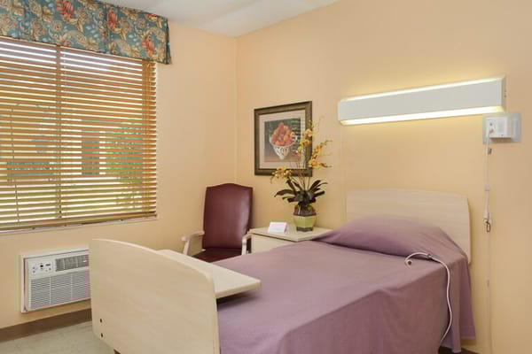 Simple private resident room with a bed and chair