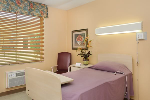 Simple private resident room with a bed and chair