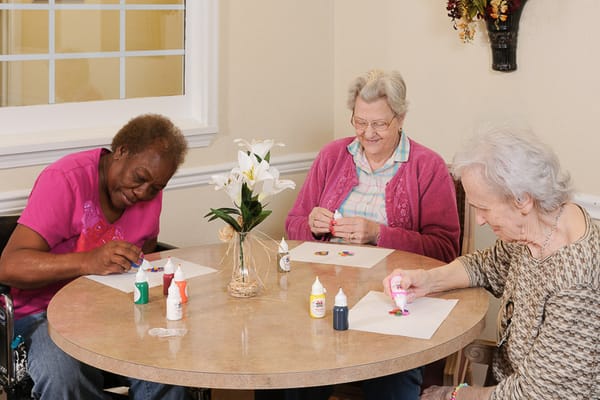 Three residents engaging in a crafting activity at a table