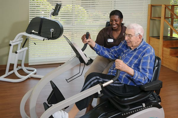 Senior resident exercising with staff assistance