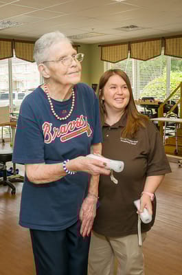 A resident and staff member using a gaming console in an activity room