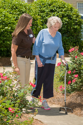 Staff assisting a resident in a garden pathway