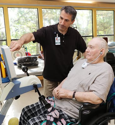 Therapist assisting a resident with rehabilitation equipment