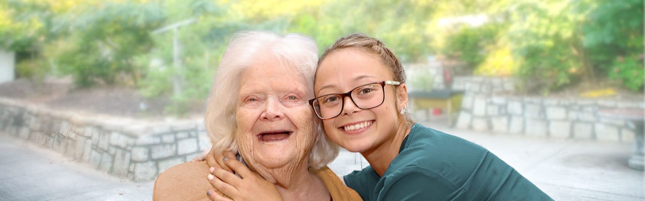 Resident and staff member smiling outdoors