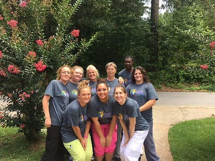 Staff members posing outside near blooming flowers