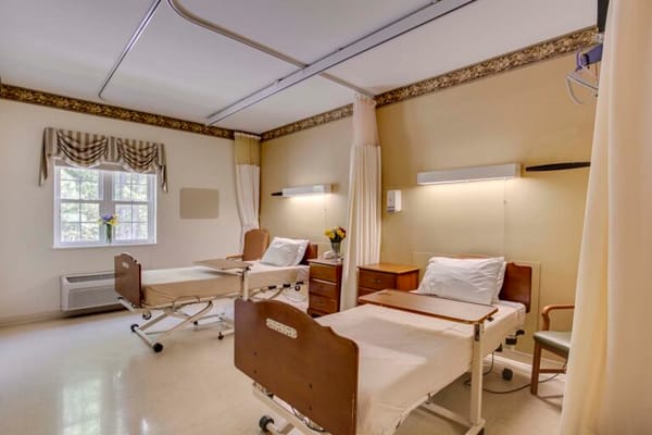 Brightly lit resident room with two beds and flowers