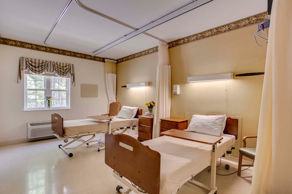 Brightly lit resident room with two beds and flowers