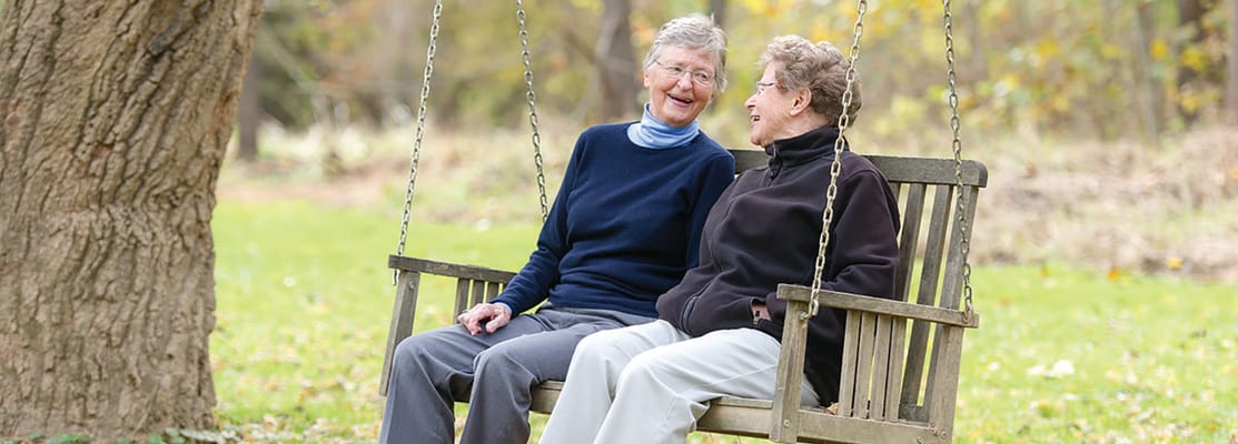 Two residents enjoying a swing in a garden