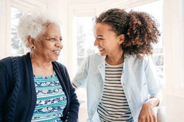 Staff member smiling with a resident in a bright room