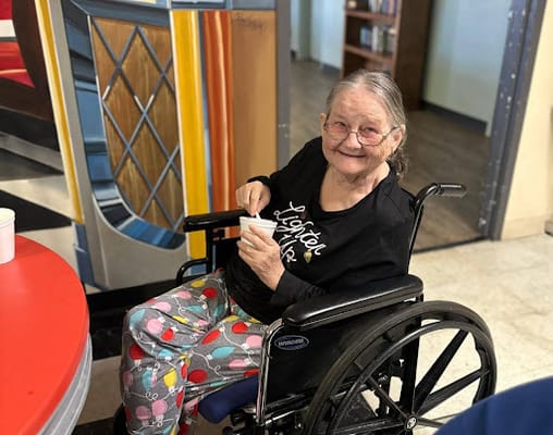 A smiling resident enjoying a treat in a common area