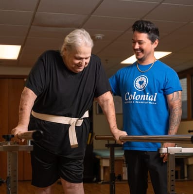 Resident assisted with rehabilitation exercises by staff member