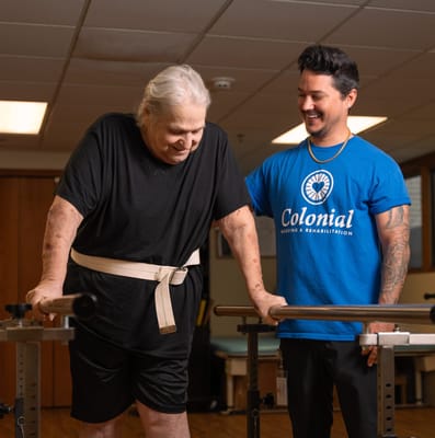 Resident assisted with rehabilitation exercises by staff member