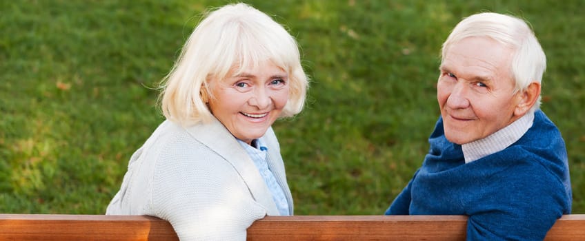 A happy senior couple sitting on a bench outdoors