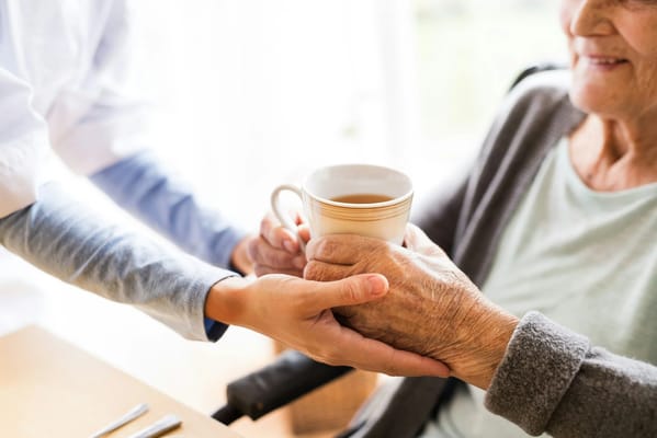 Staff member handing a cup to a smiling resident