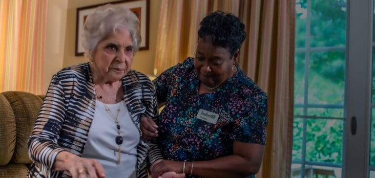 Caregiver assisting an elderly resident in a cozy living space