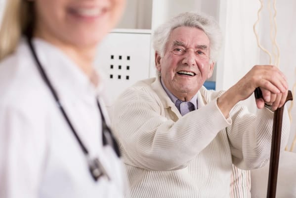 A senior man smiling while sitting with a caregiver