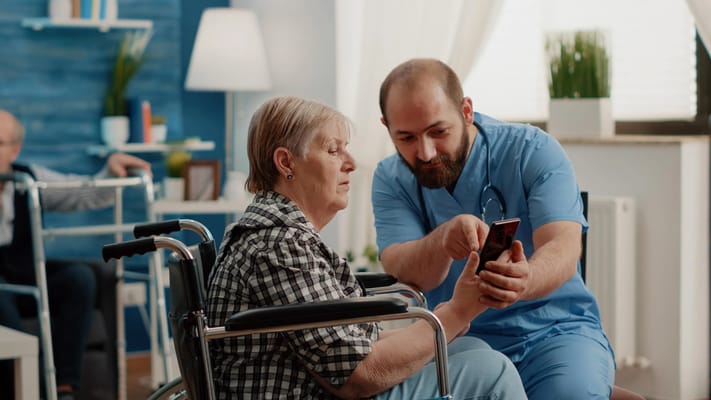 Staff assisting a resident with a smartphone in a cozy interior