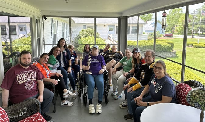 Group of residents and staff in a screened porch area