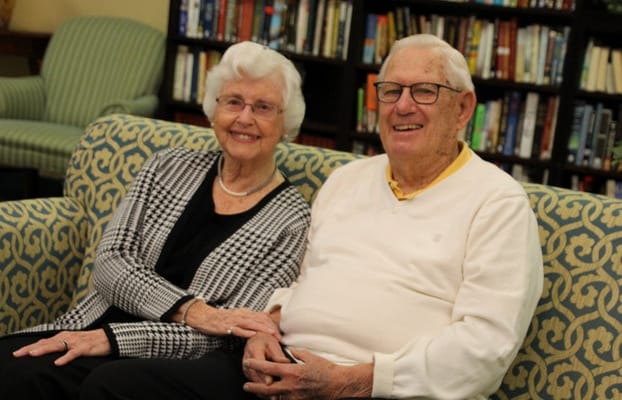 A smiling elderly couple sitting together in a cozy lounge