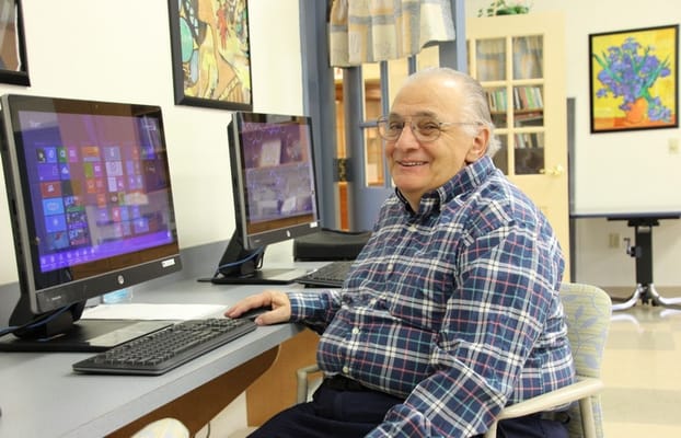 A smiling senior man sitting at a computer station