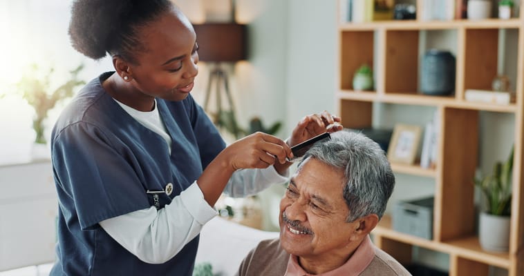 Staff grooming a resident's hair in a cozy interior