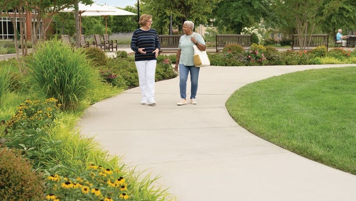 Two residents walking on a landscaped pathway