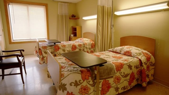A cozy resident room with two beds and floral bedding