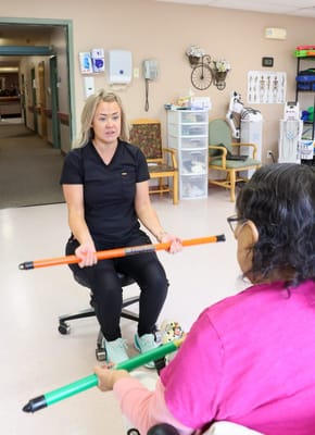 A staff member assisting a resident with exercise equipment.
