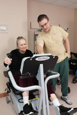 Resident using exercise equipment with staff assistance