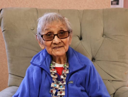 An elderly resident smiling in a cozy armchair