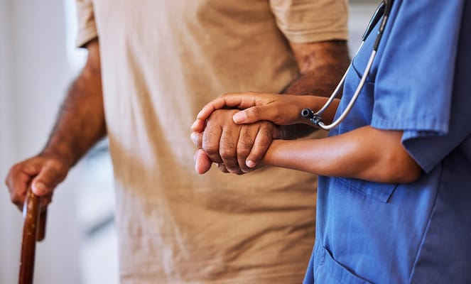 A caregiver holding a resident's hand in a caring gesture