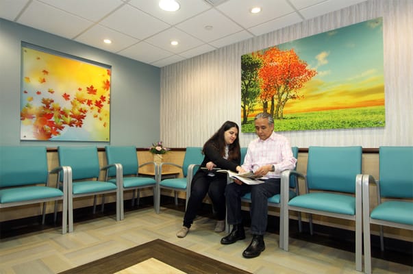 A resident and staff member reading together in a waiting area
