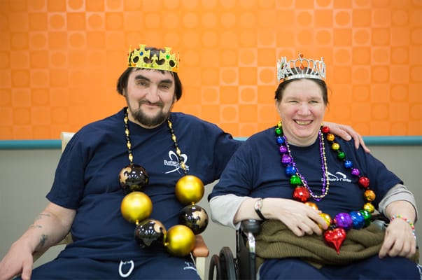 Residents celebrating with crowns and beads in an activity room
