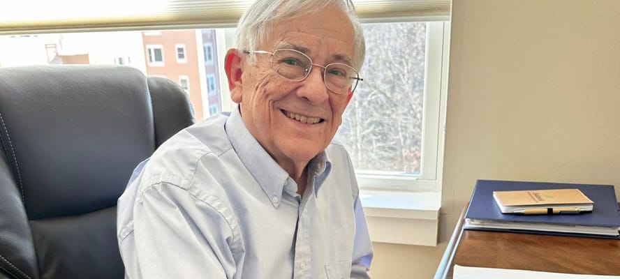 A resident smiling at their desk in an office space