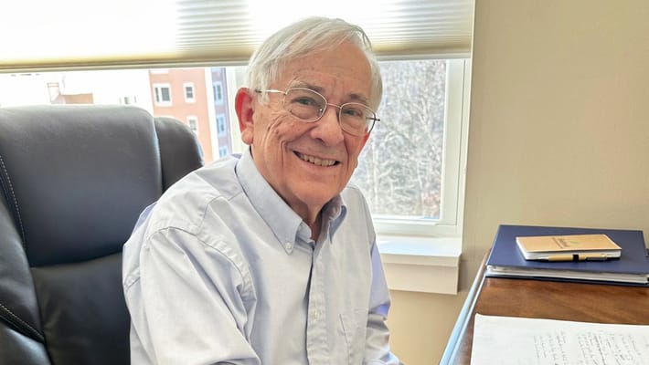 A smiling resident sitting at a desk by a window
