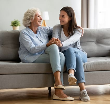 A resident and staff member sharing a joyful moment on a couch