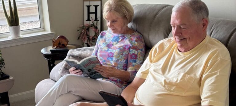 Two residents reading together in a cozy living space