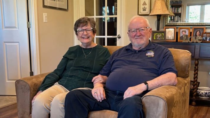 Two smiling residents sitting together in a cozy living room