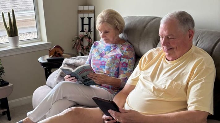Two residents reading together in a cozy living area
