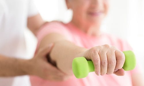 Resident exercising with a green dumbbell during therapy