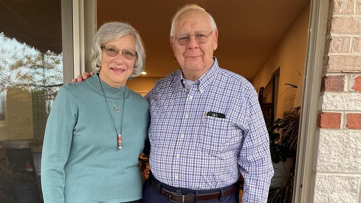 Two residents smiling on a balcony entrance