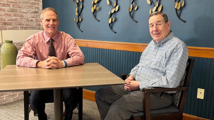 Two men sitting at a table in an activity room