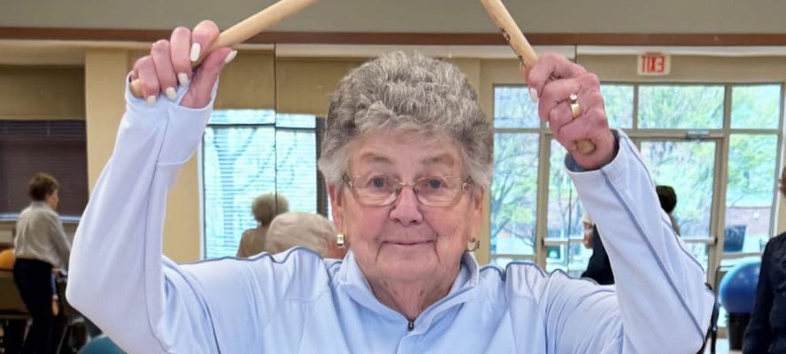Resident participating in a lively activity with drumsticks