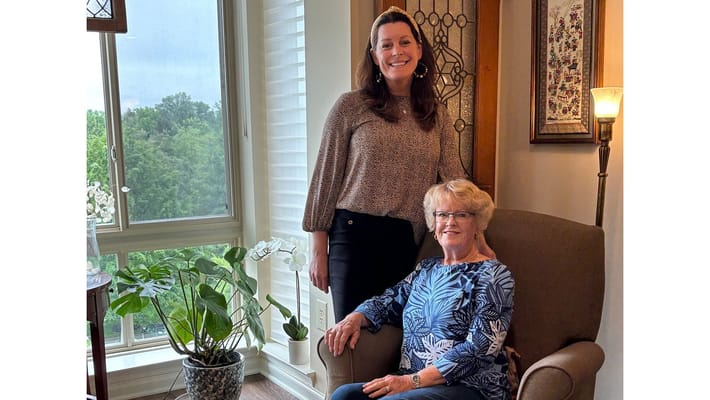 A staff member and resident posing together in a cozy living space