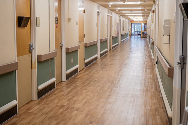 Bright hallway with resident room doors and wooden floor