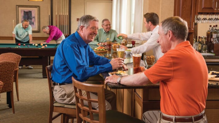 Men socializing at a bar with food and drinks