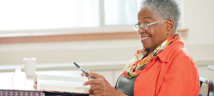 An older woman reading a book with a smile